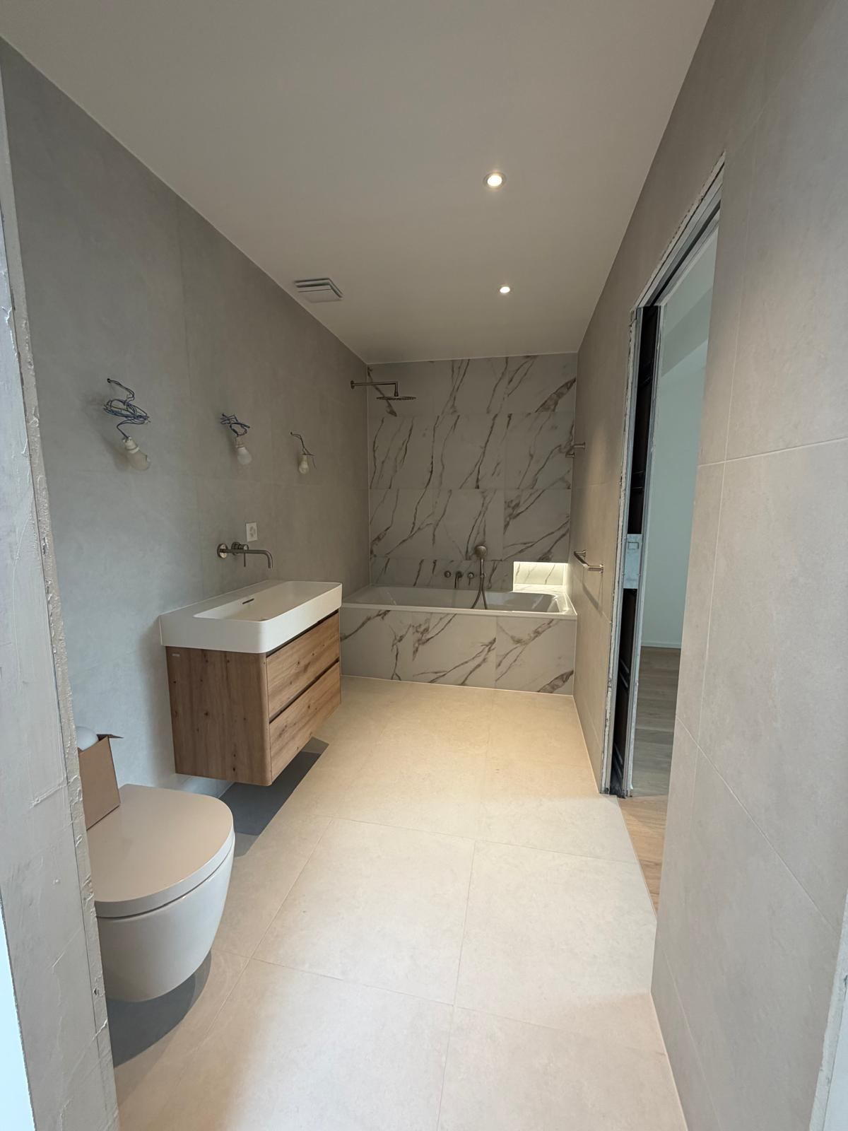 Salle de bain carrelée effet marbre avec baignoire habillée en céramique